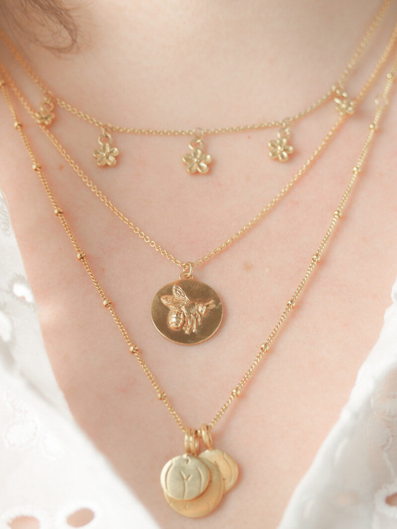 gold bee coin necklace layered on model