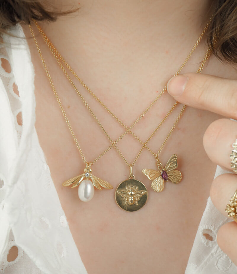 pearl bee necklace with butterfly and bee coin necklaces on model