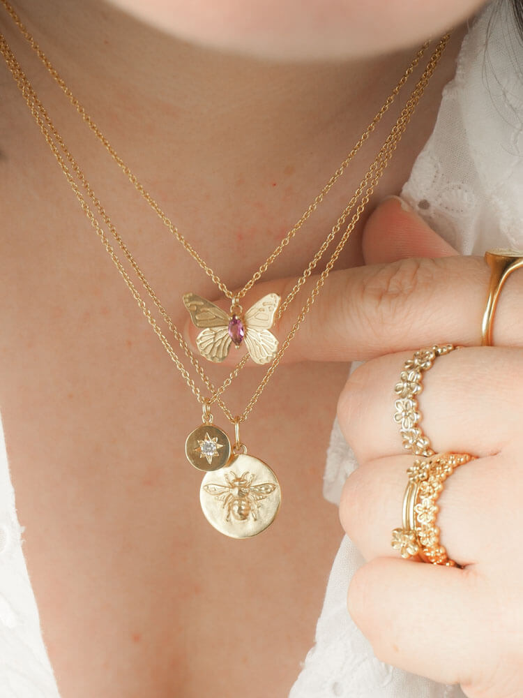 Gold bee coin necklace stack with butterfly and star necklace