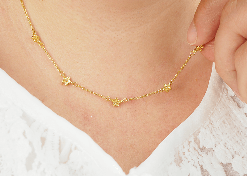 yellow gold delicate necklace with small flowers dotted along the chain