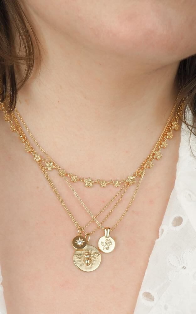 Bee Coin necklace in gold shown with star star and flower necklaces