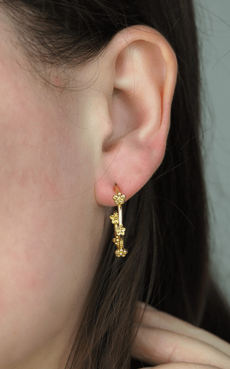 gold hoop earrings with tiny flowers on model