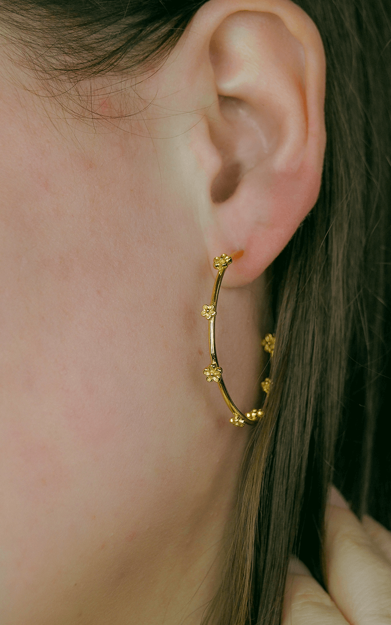 gold hoop earrings with small flowers on model