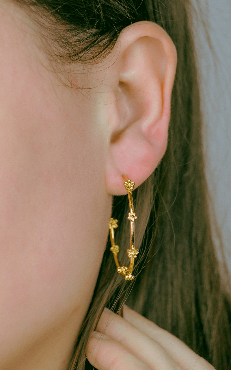 gold hoop earrings with tiny flowers dotted along hoop on model
