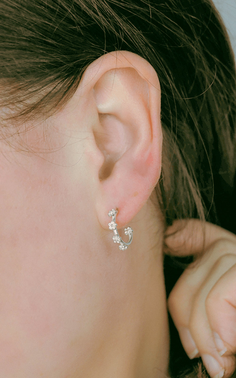 silver mini flower hoop earrings on model